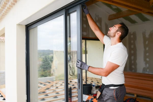 Mann beim Einbau einer Hebeschiebetuer der bei der Fenstermontage einiges beachtet.