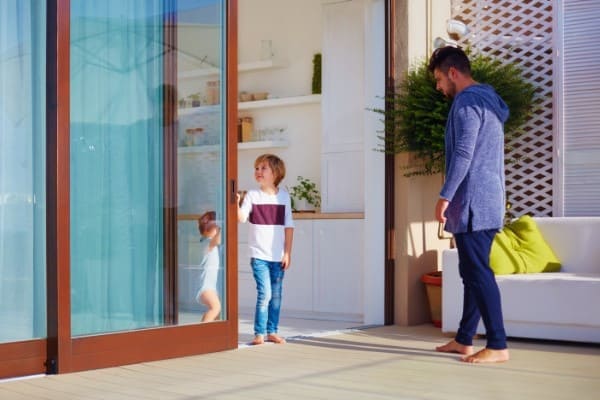 Mann und Kind auf Terrasse an Fenster