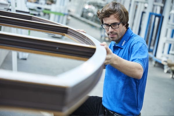 Mitarbeiter der Firma FeBa Fensterbau GmbH überprüft ein Rundbogen Fenster auf seine Qualität.