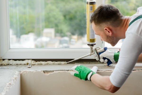 Mann dichtet innere Fensterseite unten ab Mann dichtet innere Fensterseite unten ab