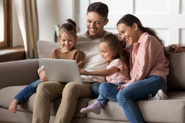 Familie konfiguriert schwarze Fenster online auf Couch.