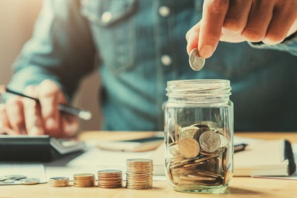 Mann stapelt Geld Münzen symbolisch für Geld sparen.