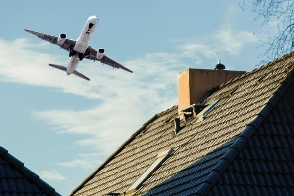 Flugzeug über Haus mit schalldämmenden Plastikfenstern Flugzeug über Haus mit schalldämmenden Plastikfenstern