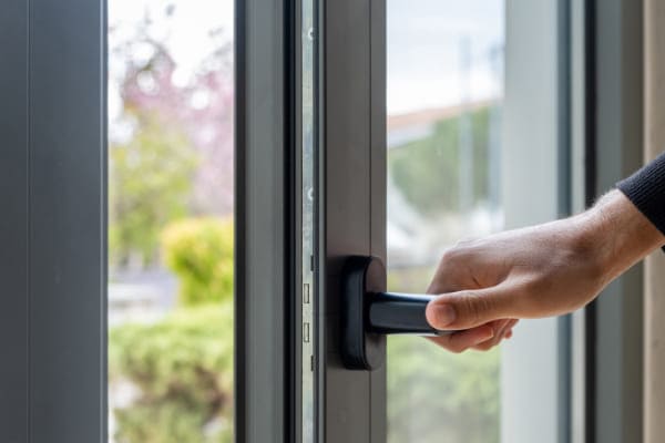 Person öffnet per Fenstergriff ein Fenster