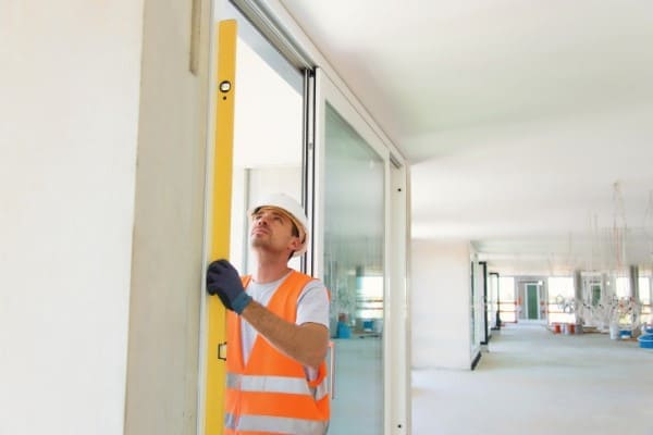 Mann baut bodentiefes Fenster nach RAL Vorschrift ein