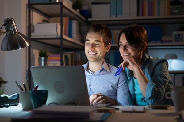 Pärchen sitzt an einem Schreibtisch und konfiguriert auf Fensterhandel.de Ihre Kunststofffenster.