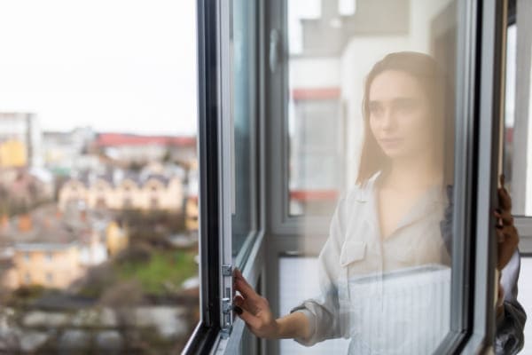 Frau bedient auf komfortable Weise ein Fenster aus Aluminium.