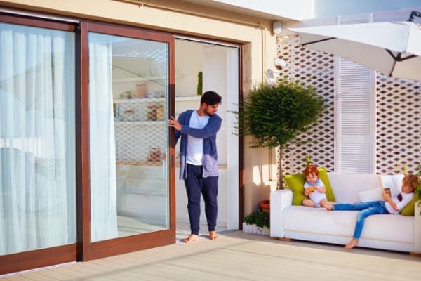 Mann stellt seiner Familie Besonderheiten des Terrassenfensters vor. Mann stellt seiner Familie Besonderheiten des Terrassenfensters vor.