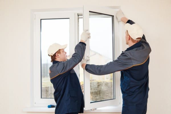 Zwei Personen hängen den Fensterflügel ein Zwei Personen hängen den Fensterflügel ein