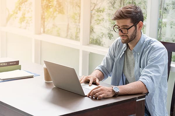 Mann sitzt am Laptop und bestellt Fenster mit Dreifachverglasung