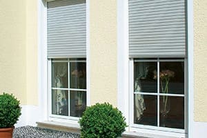 Glückliches Paar sitzt auf dem Sofa. Im Hintergrund große Fensterfronten mit Vorhang auf der Seite.