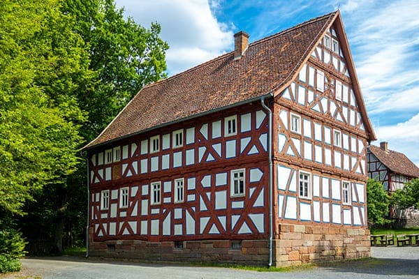 Großes Fachwerkhaus mit roten Balken und weißen Kunststofffenstern.