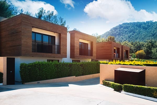 Moderne Häuser mit grüner Pflanzenwand und schwarzen Fenstern mit Aluschale außen.