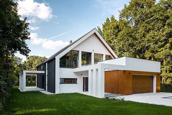 Modernes Haus von außen gesehen mit Garten und vielen unterschiedlichen Fenstertypen.