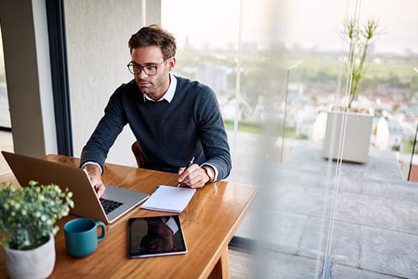 Mann sitzt vor dem Laptop und konfiguriert seine Fenster auf der Internetseite FensterHandel.de. 