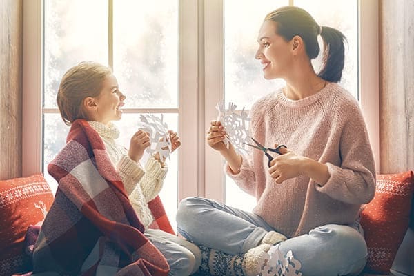 Familie bastelt vor gut gedämmten Fenster mit U-Wert Familie bastelt vor gut gedämmten Fenster mit U-Wert