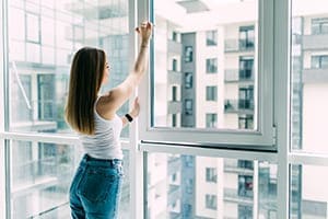 Frau macht Fenster auf.