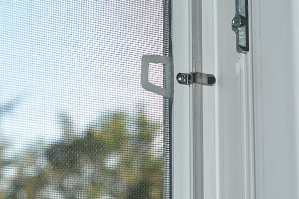 Geöffnetes Fenster mit grauer Dichtung, geschlossenem Insektenschutzgitter und einem Schließstück Geöffnetes Fenster mit grauer Dichtung, geschlossenem Insektenschutzgitter und einem Schließstück