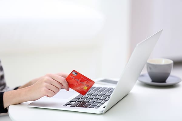 Frau sitz am Leptop mit Kreditkarte.