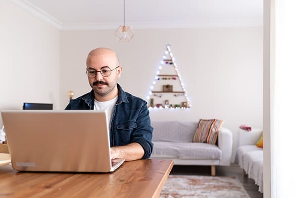 Mann sitz im Wohnzimmer vor Leptop und bestellt online.