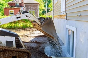 Kellerfenster von außen gesehen Bagger schuttet Loch zu.