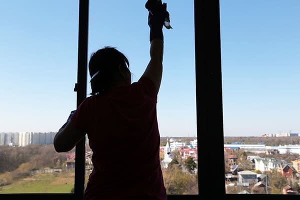 Frau reinigt ein Kunststoff-Alu-Fenster von innen