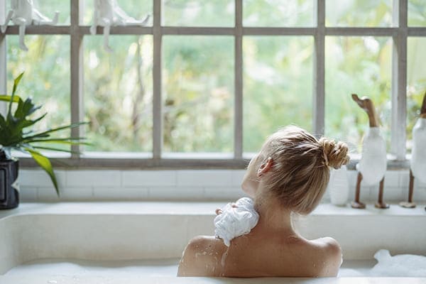 Frau sitzt in der Badewann und schaut aus dem Fenster. Frau sitzt in der Badewann und schaut aus dem Fenster.
