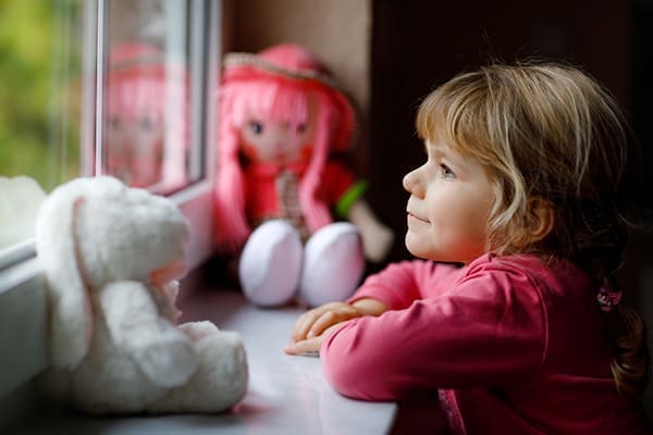 Mädchen schaut lächelnd aus dem Fenster.