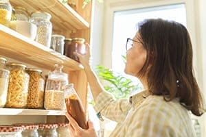 Frau Räum Gläser ins Regal im Hintergrund ein schönes Kunststofffenster.