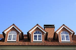 Drei Rundbogengieblfenster mit weißen Sprossen.