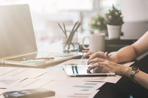 Frau berät Kunden am Telefon und arbeitet mit Tablet und Laptop.