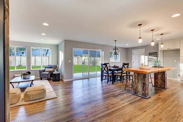 Die offene Inneneinrichtung mit poliertem Holzfußboden Esstisch und Schiebetüren auf einen eingezäunten Hinterhof. Die offene Inneneinrichtung mit poliertem Holzfußboden Esstisch und Schiebetüren auf einen eingezäunten Hinterhof.