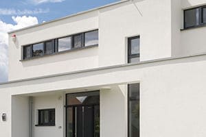 Neubau von außen geshen in weiß mit Anthrazitfarbenen Fenstern.