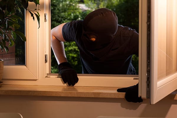 Einbrecher will über offenes Zweiflügelfenster reinspringen.