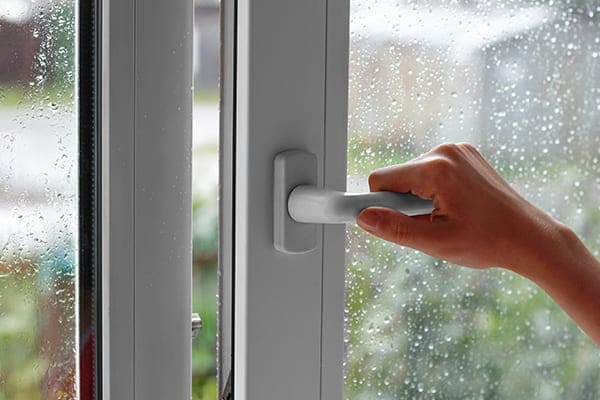 Frau schließt Zweiflügeliges Fenster.